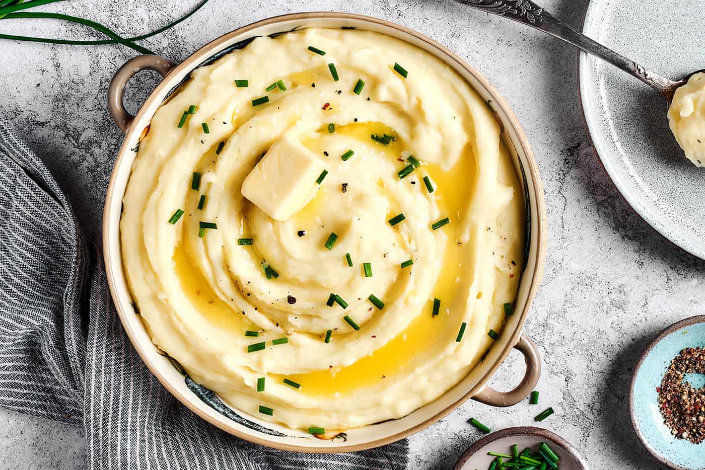 A large bowl of mashed potatoes with buttermilk, topped with melted butter and chives