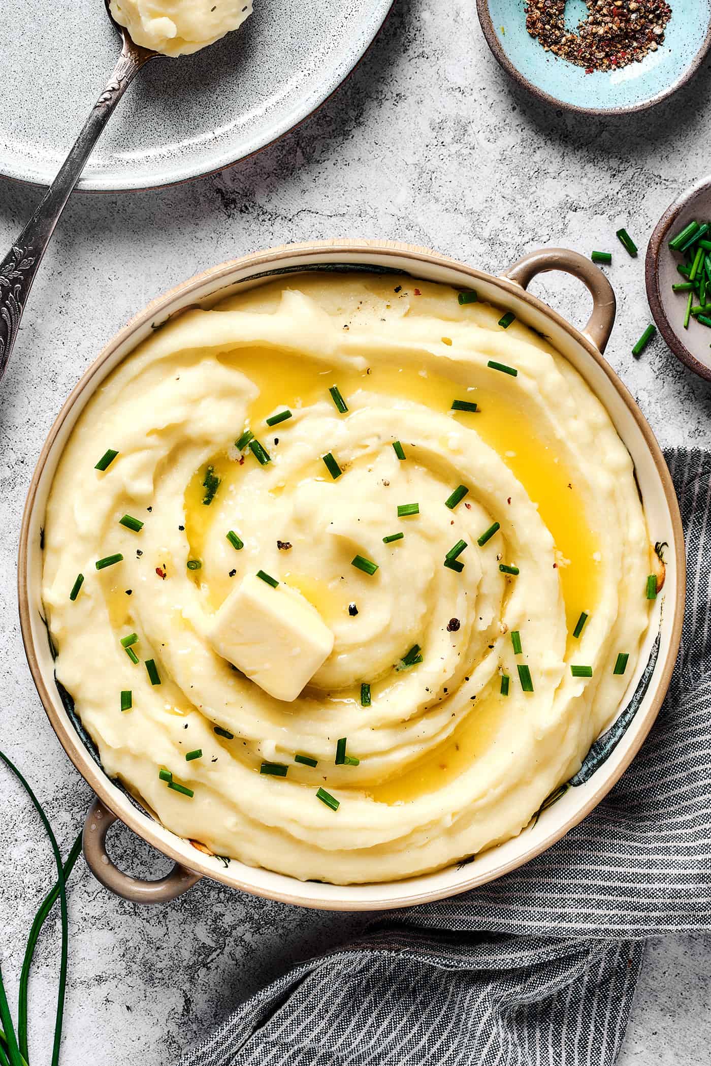 A large bowl of mashed potatoes with buttermilk, topped with melted butter and chives