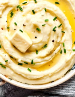 overhead photo of large bowl of mashed potatoes with buttermilk, topped with melted butter and chives