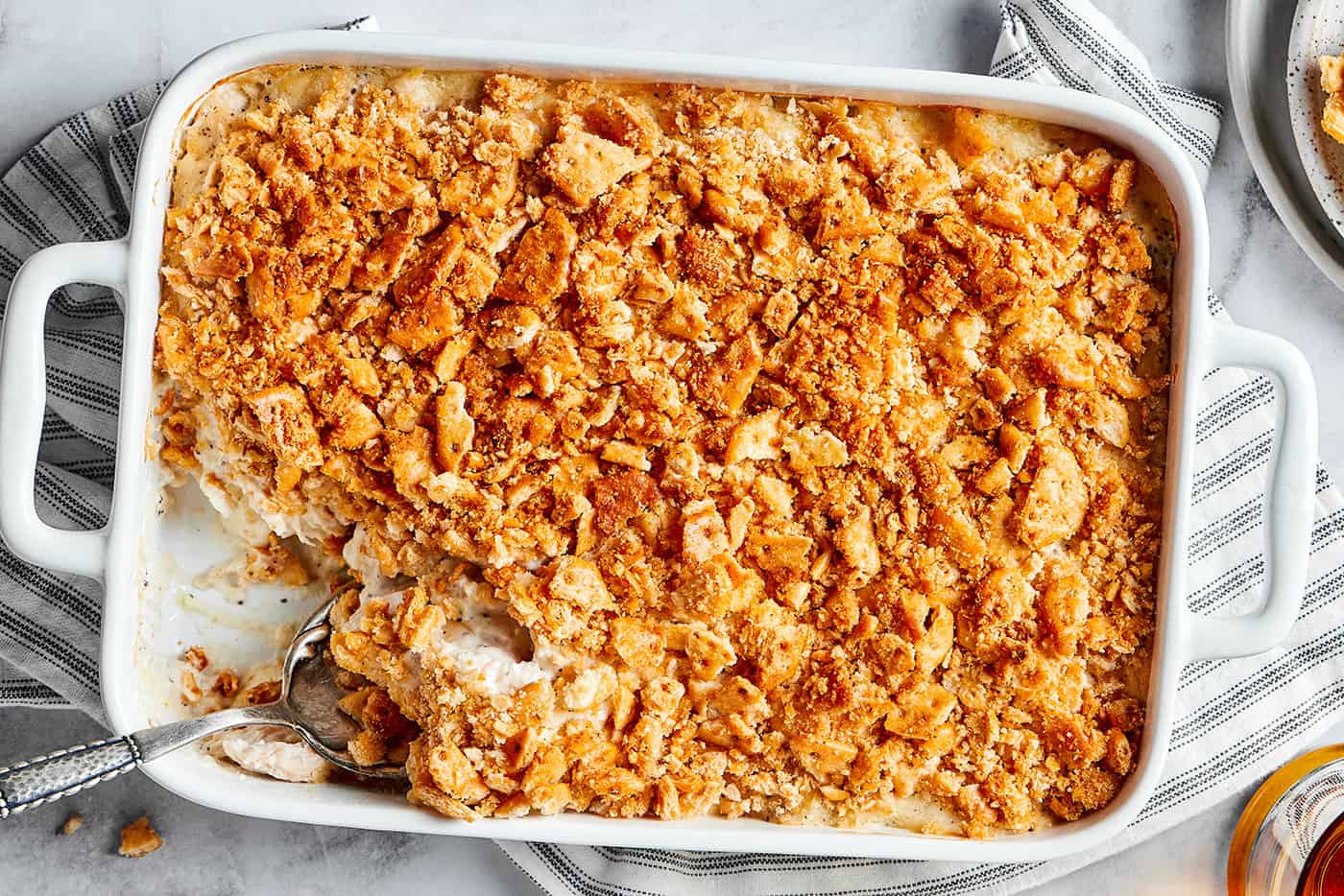 poppy seed chicken casserole baked in a white rectangular dish, with a spoon in it