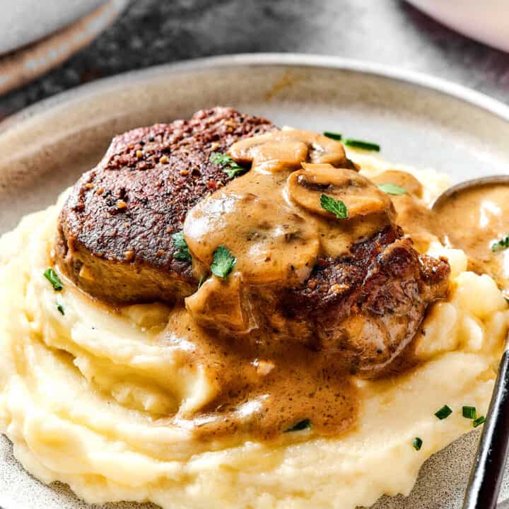 a steak with creamy mushroom sauce over mashed potatoes