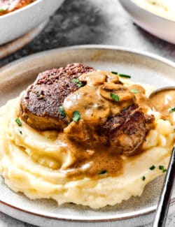 a steak with creamy mushroom sauce over mashed potatoes