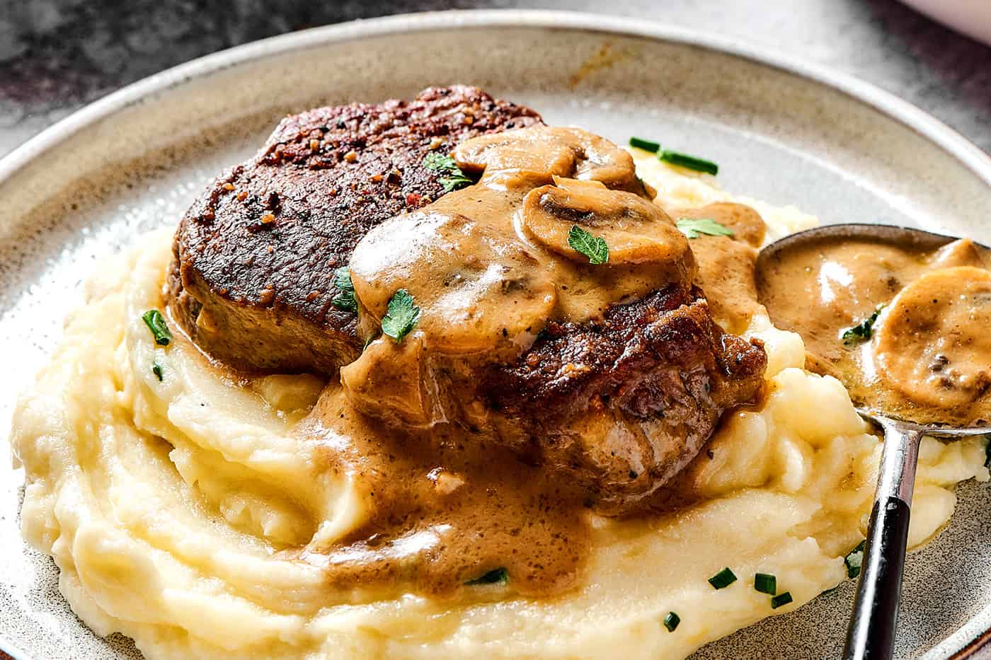 a steak with creamy mushroom sauce over mashed potatoes