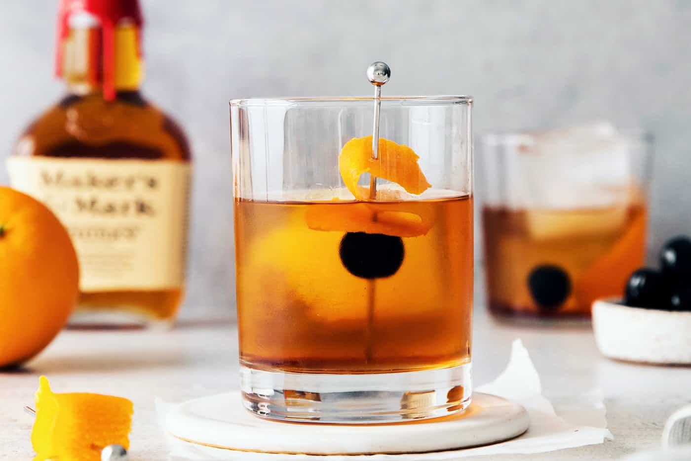 An old fashioned in a lowball glass with a large ice cube and an orange  peel