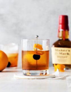 A manhattan cocktail in front of a bottle of whiskey