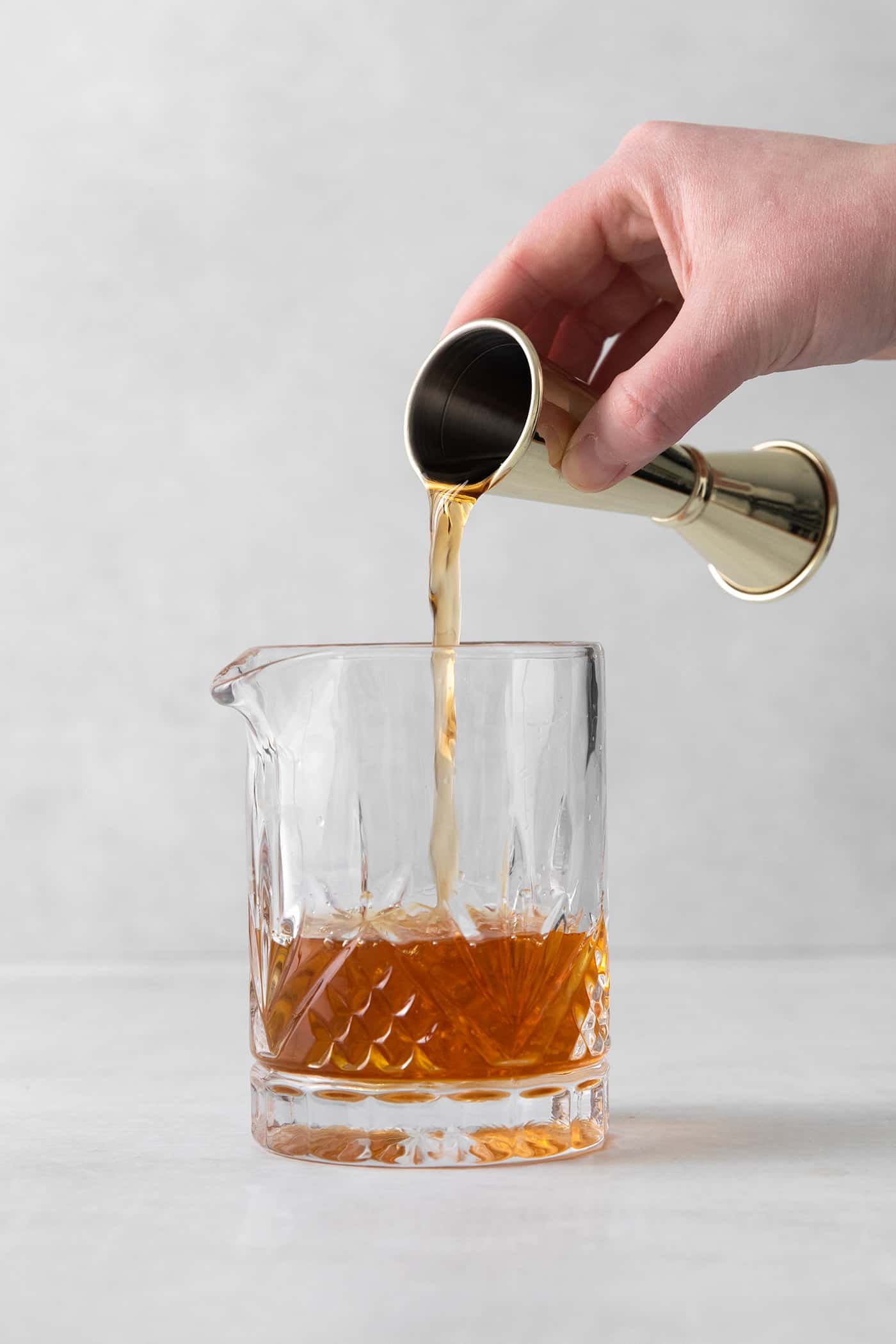 A hand pouring bourbon into a glass