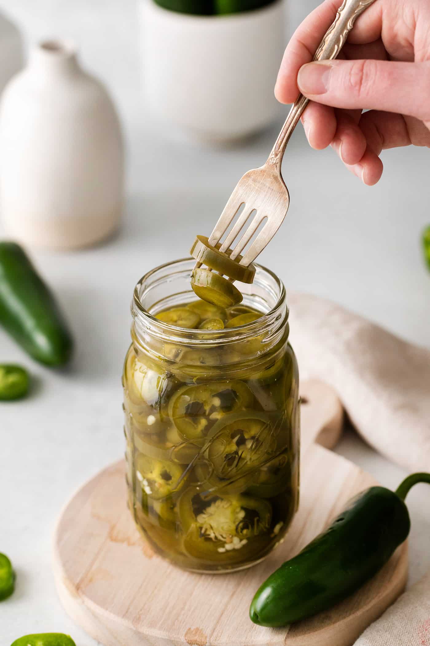 A fork pulling a jalapeno slice from a jar
