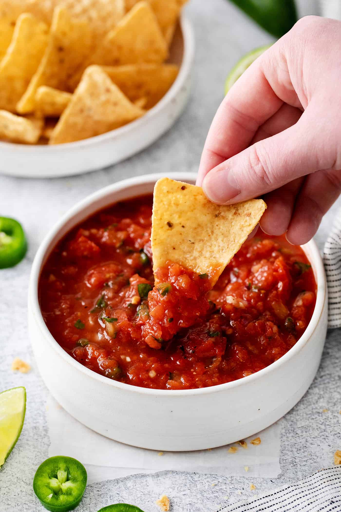 A hand dipping a chip into restaurant style salsa