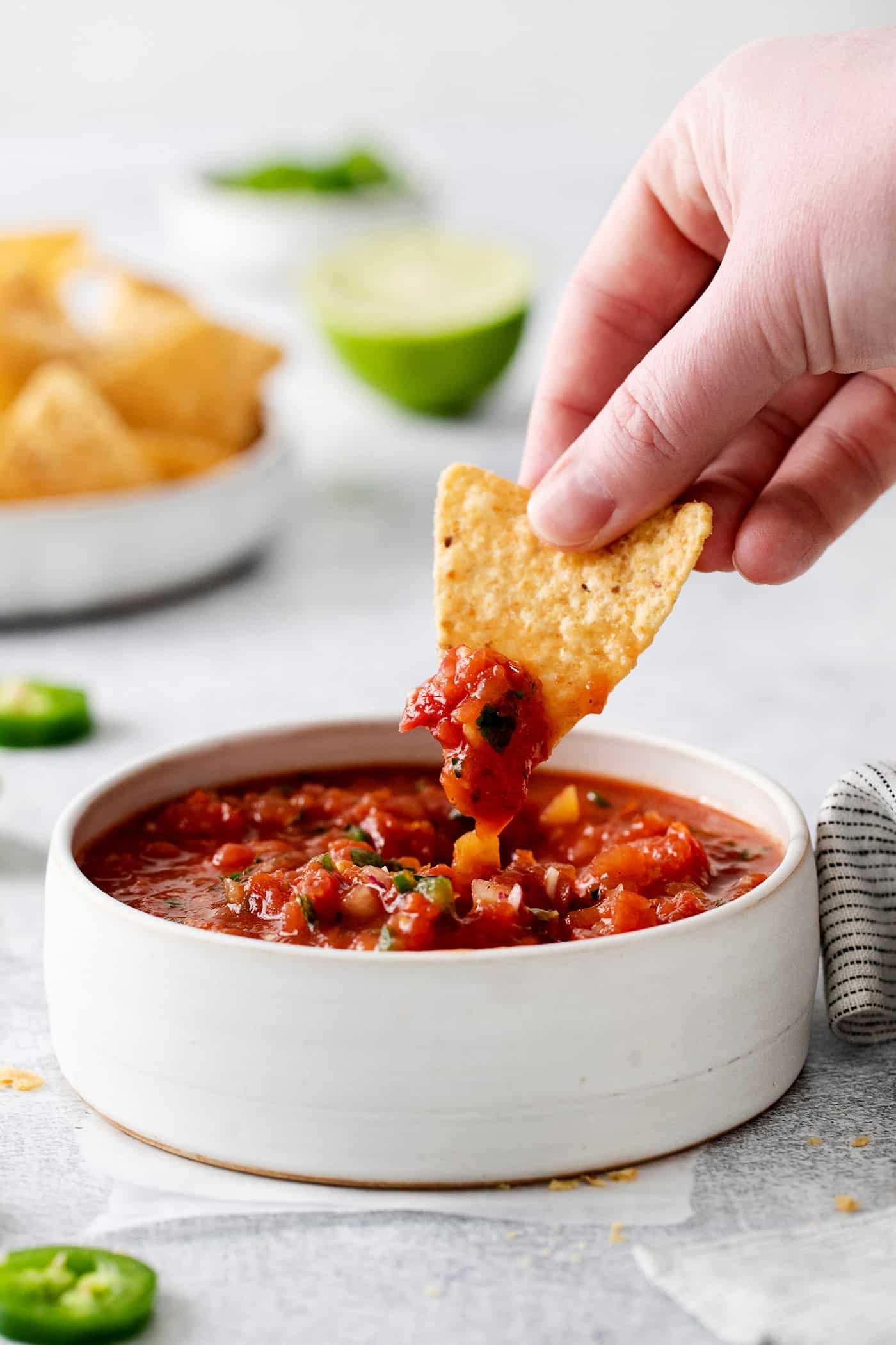 A hand holding a chip dipped in salsa