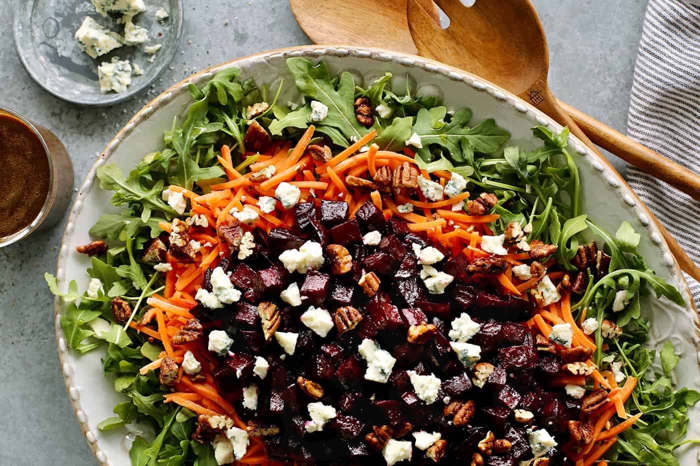 a large platter of salad with arugula, carrots, and roasted beets