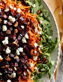 a large platter of salad with arugula, carrots, and roasted beets