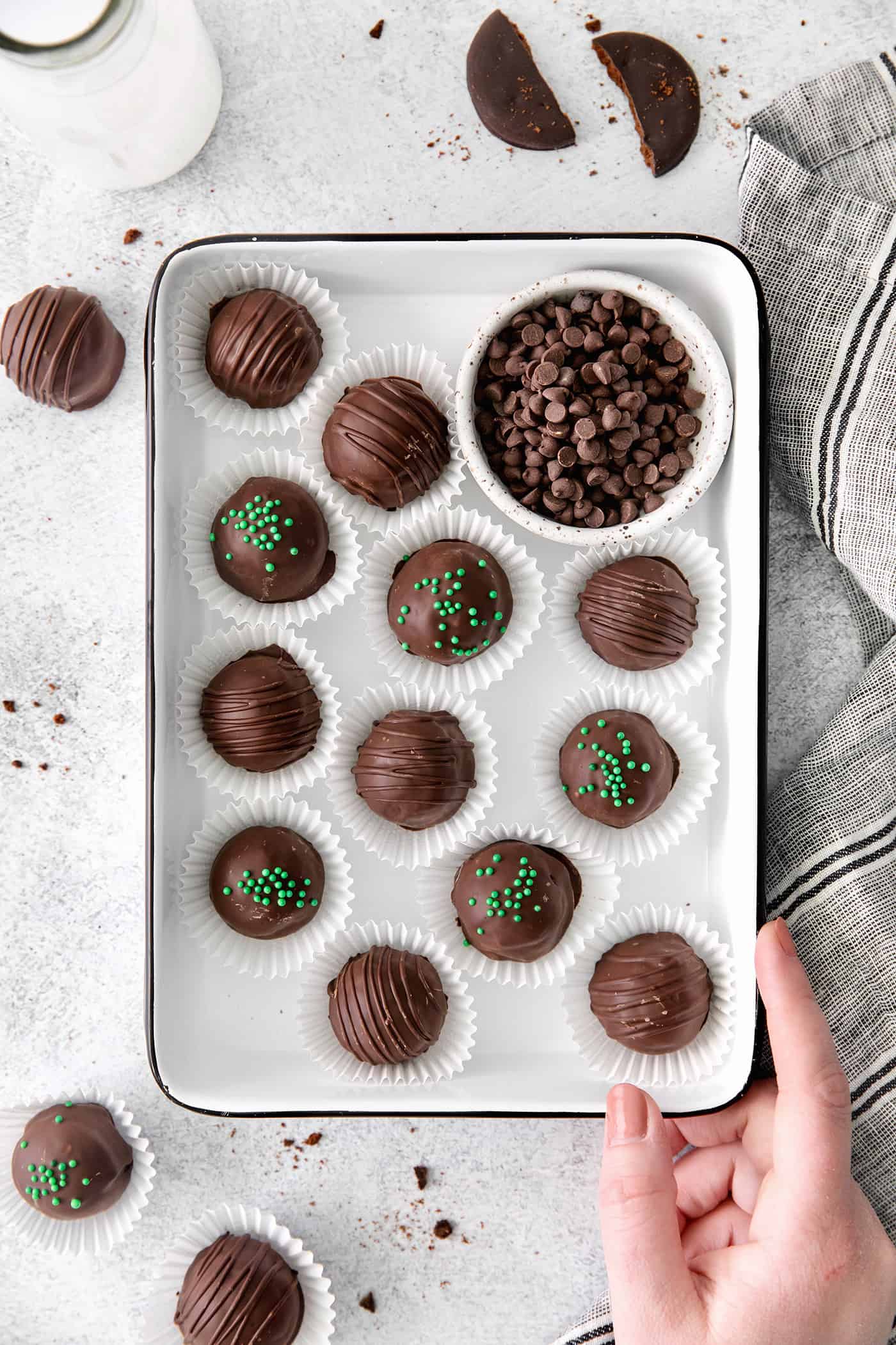 A hand holding a tray of mint chocolate truffles