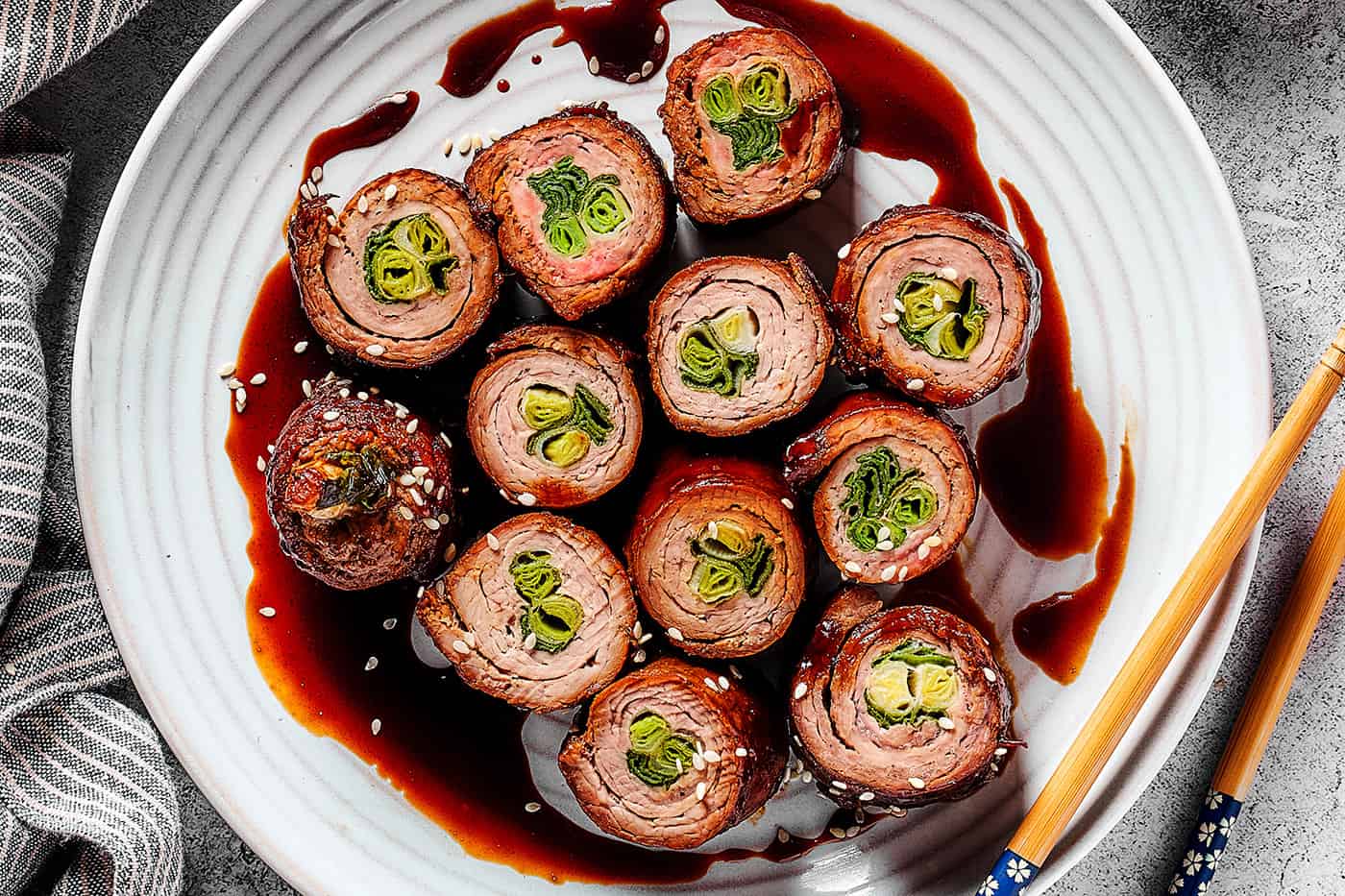 beef negimaki rolls on a white plate