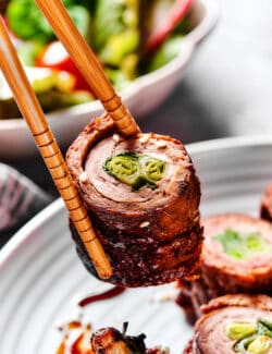 chopsticks holding a beef negimaki roll