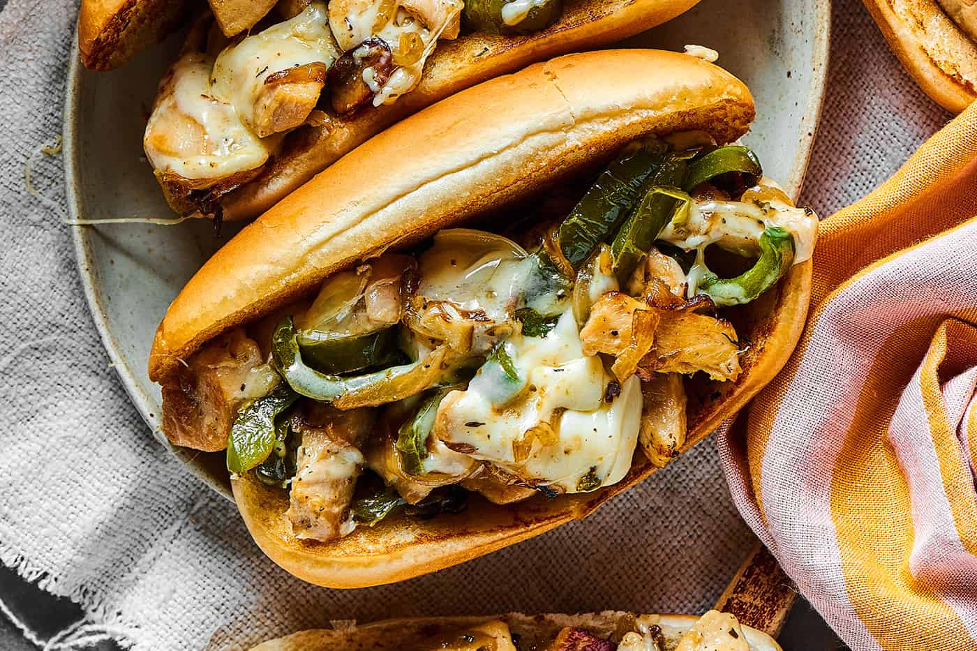 overhead photo of assembled sandwich with a hoagie roll, chicken, green pepper, and melted cheese