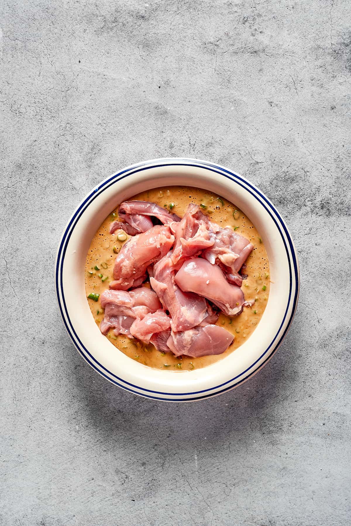 Pieces of chicken thighs added to mochiko chicken batter