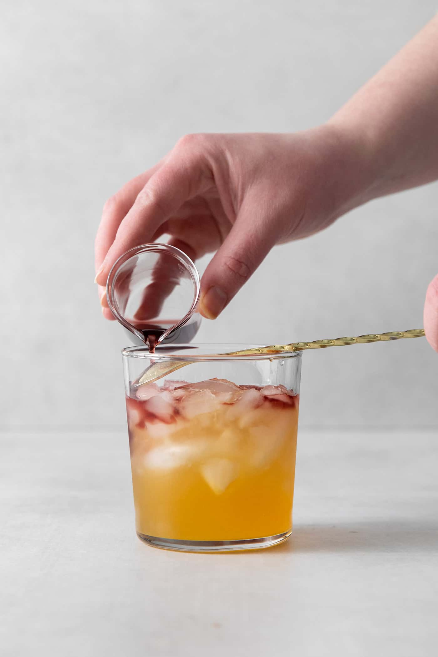 Red wine being poured into a cocktail glass over a spoon