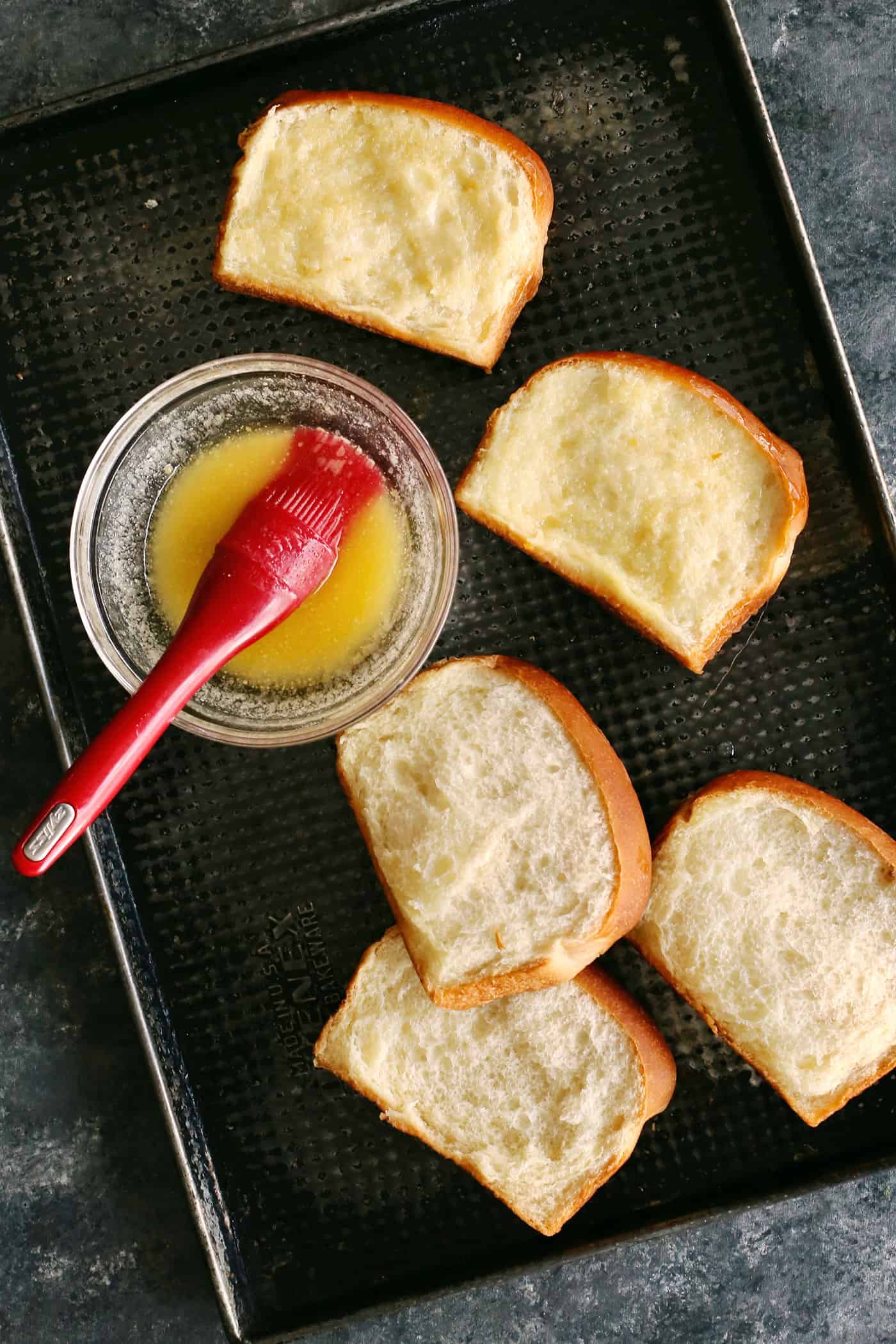 Melted butter being brushed on slices of toast