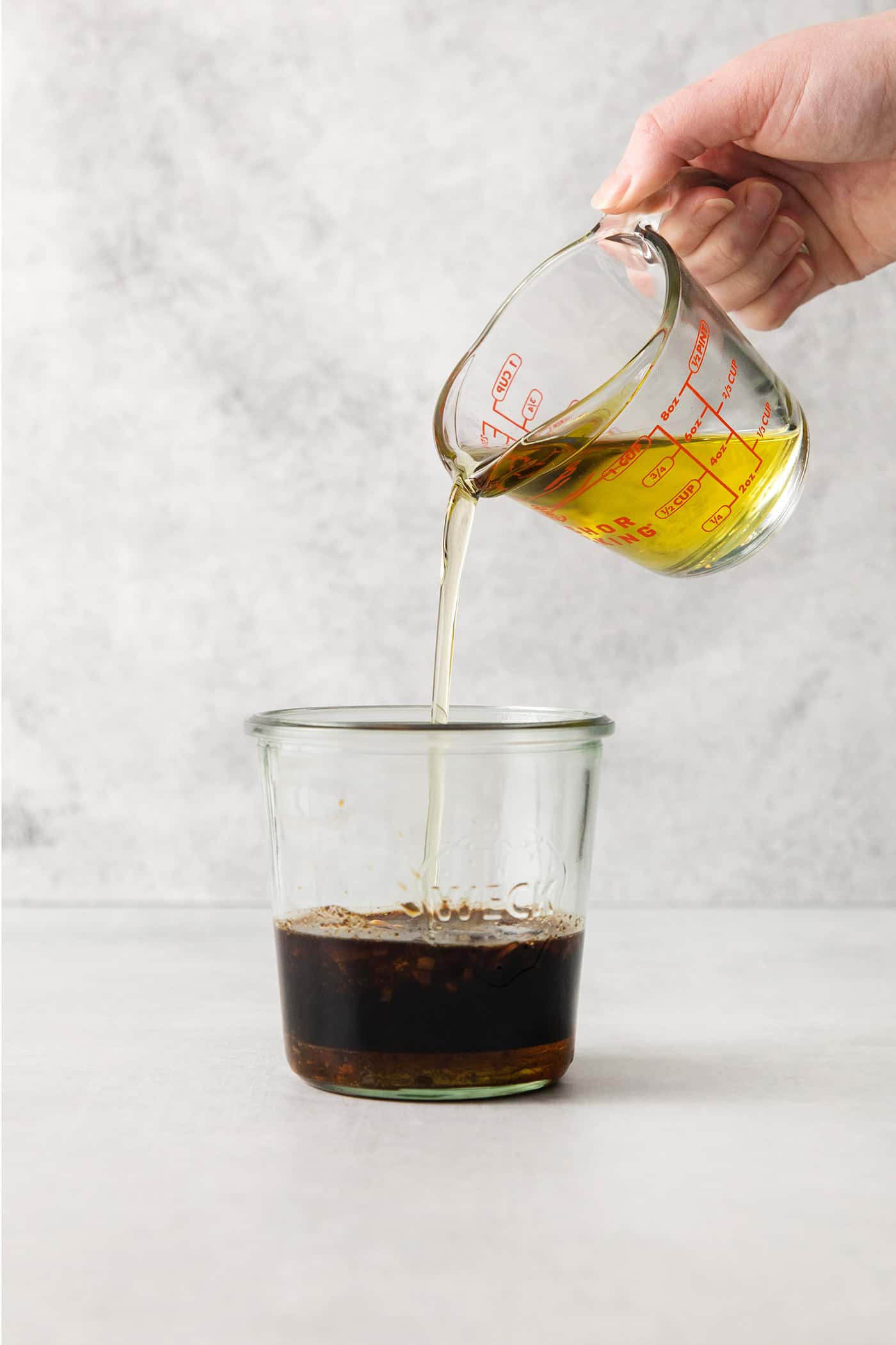 Olive oil being poured into a jar with balsamic vinegar