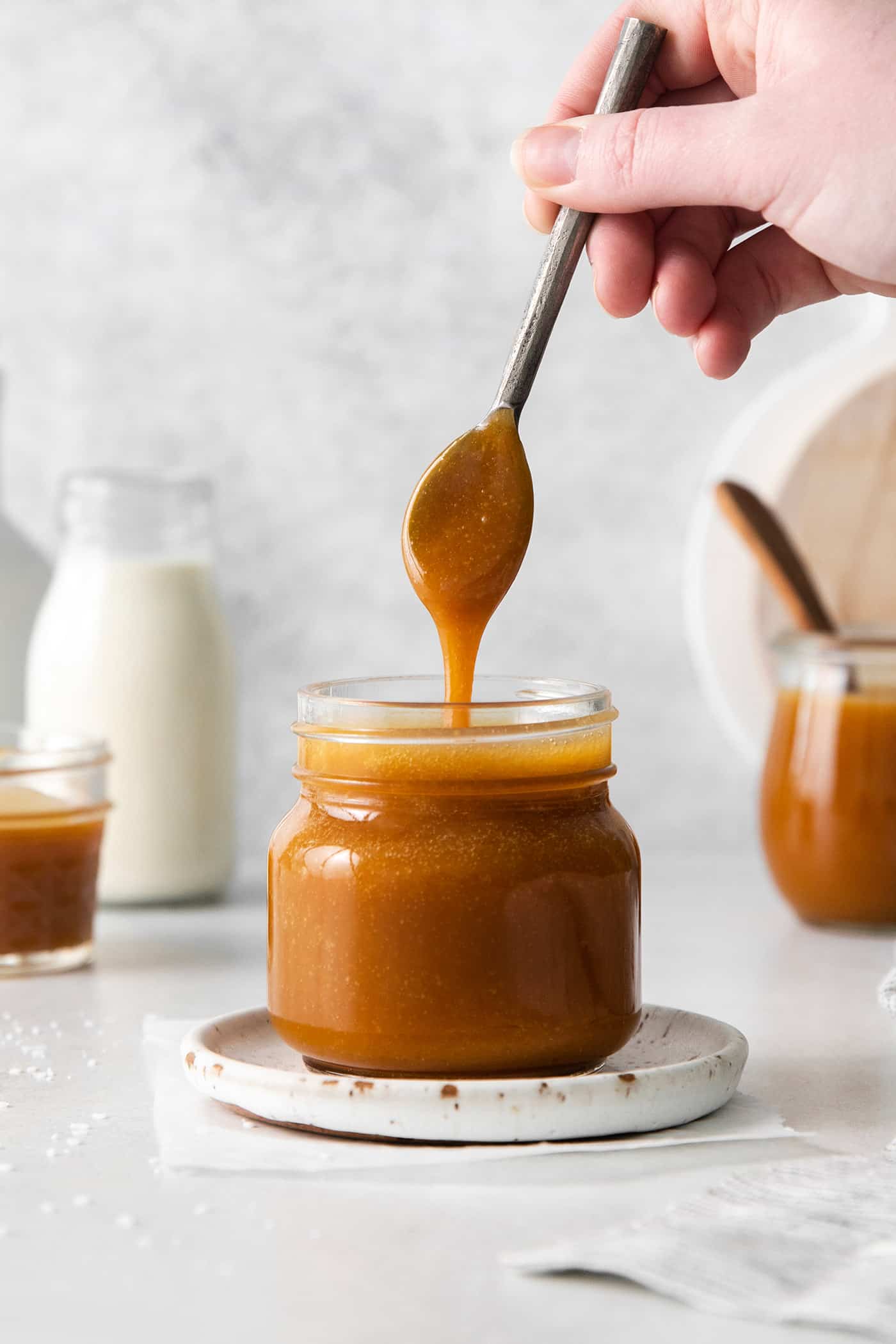 Caramel Buttermilk Syrup is creamy, sweet, and buttery. It's the perfect topping for pancakes, waffles, ice cream, and more. A spoon dripping caramel sauce back into the jar