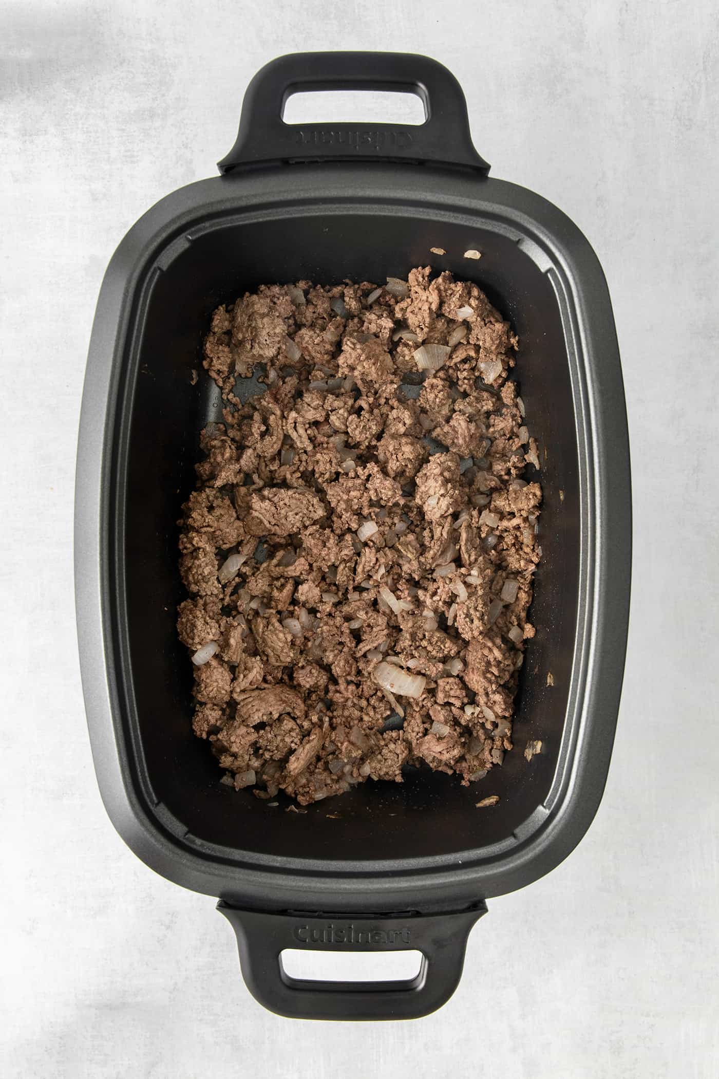 Cooked ground beef in the bottom of a slow cooker