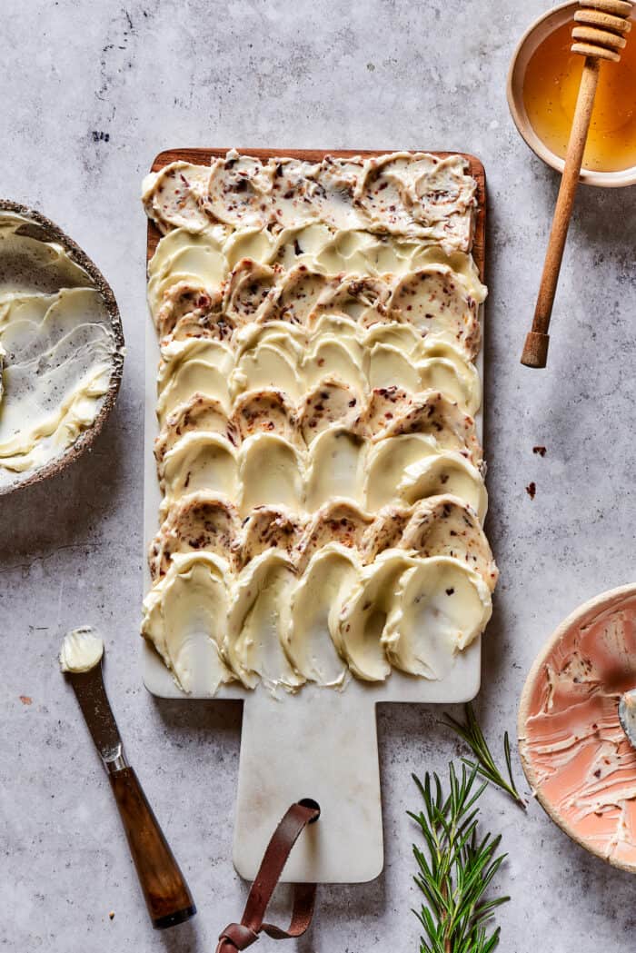 Salted butter and bacon butter spread on a wooden cutting board