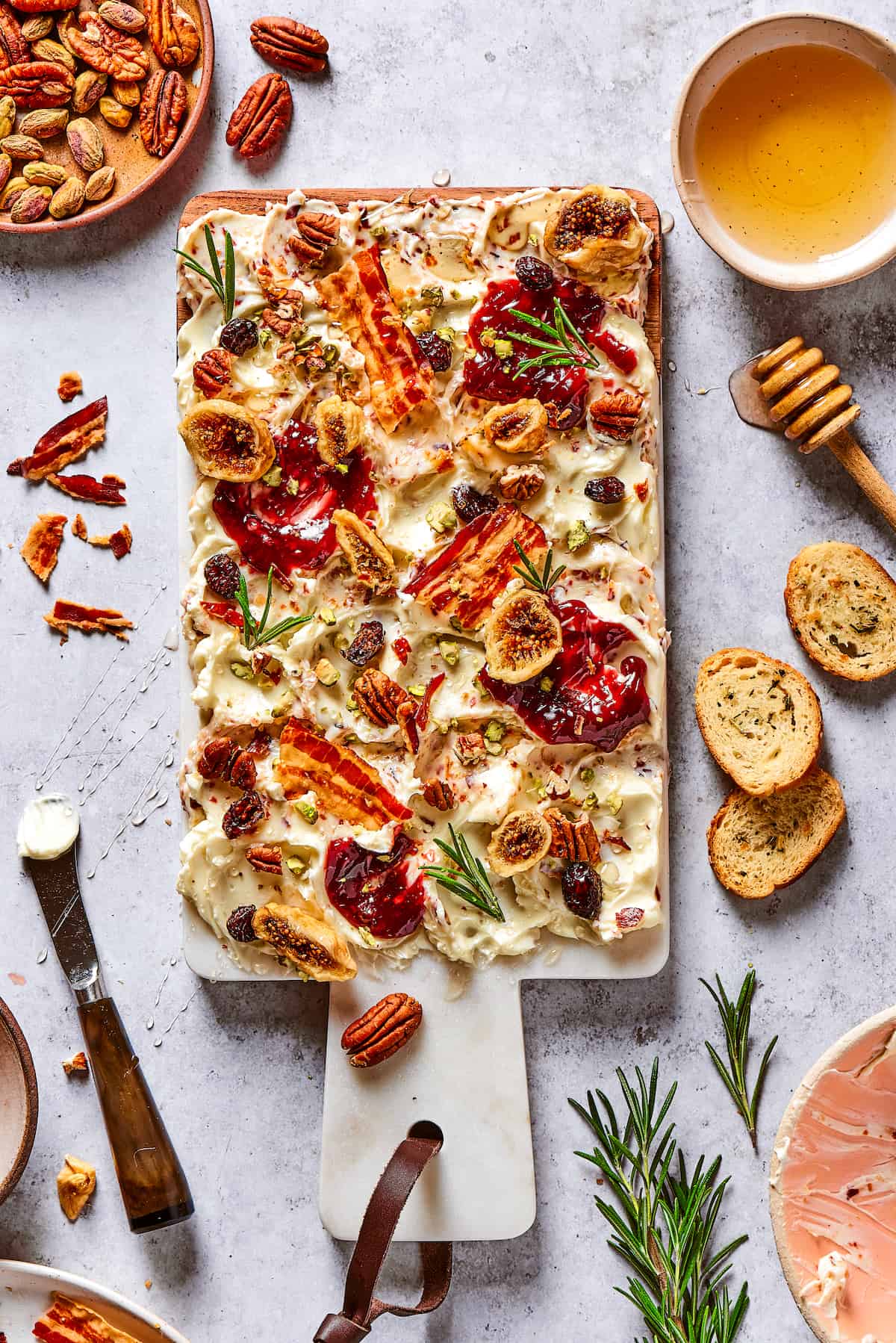 Overhead view of a butter board with bacon and dried fruits