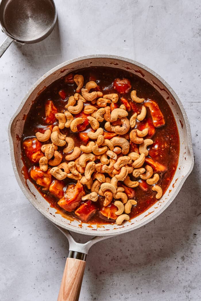 Cashews added to chicken in a frying pan