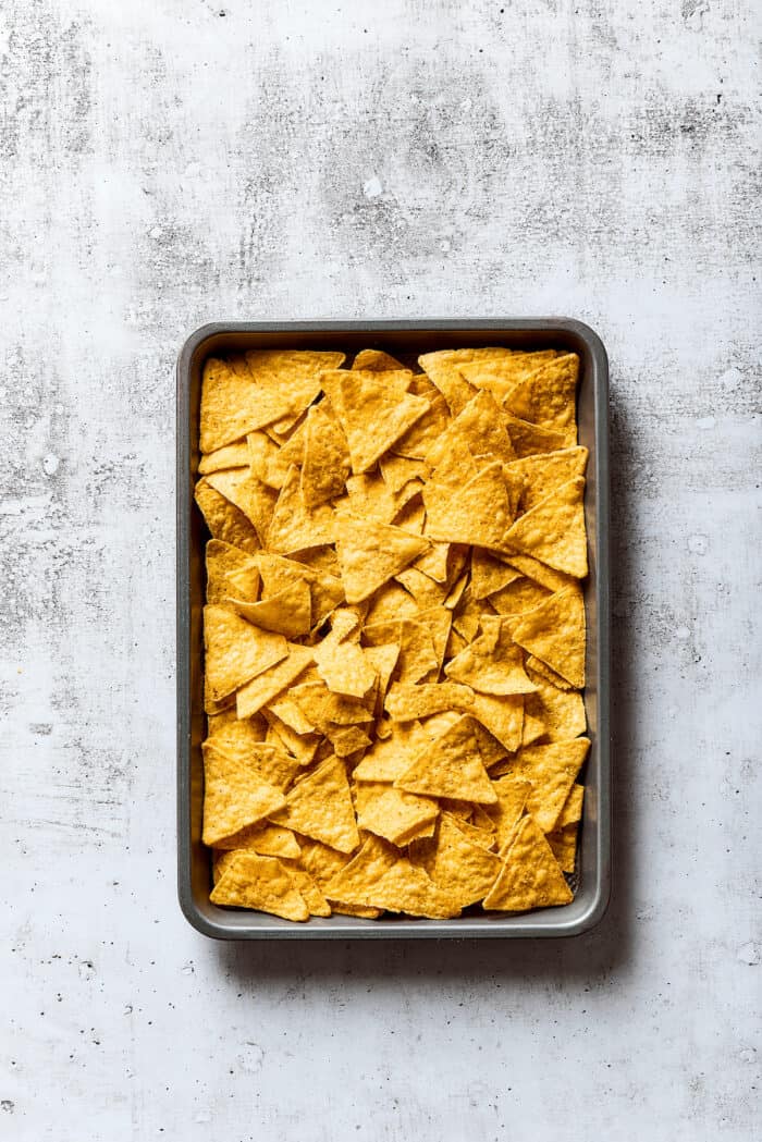 Tortilla chips spread on a baking sheet