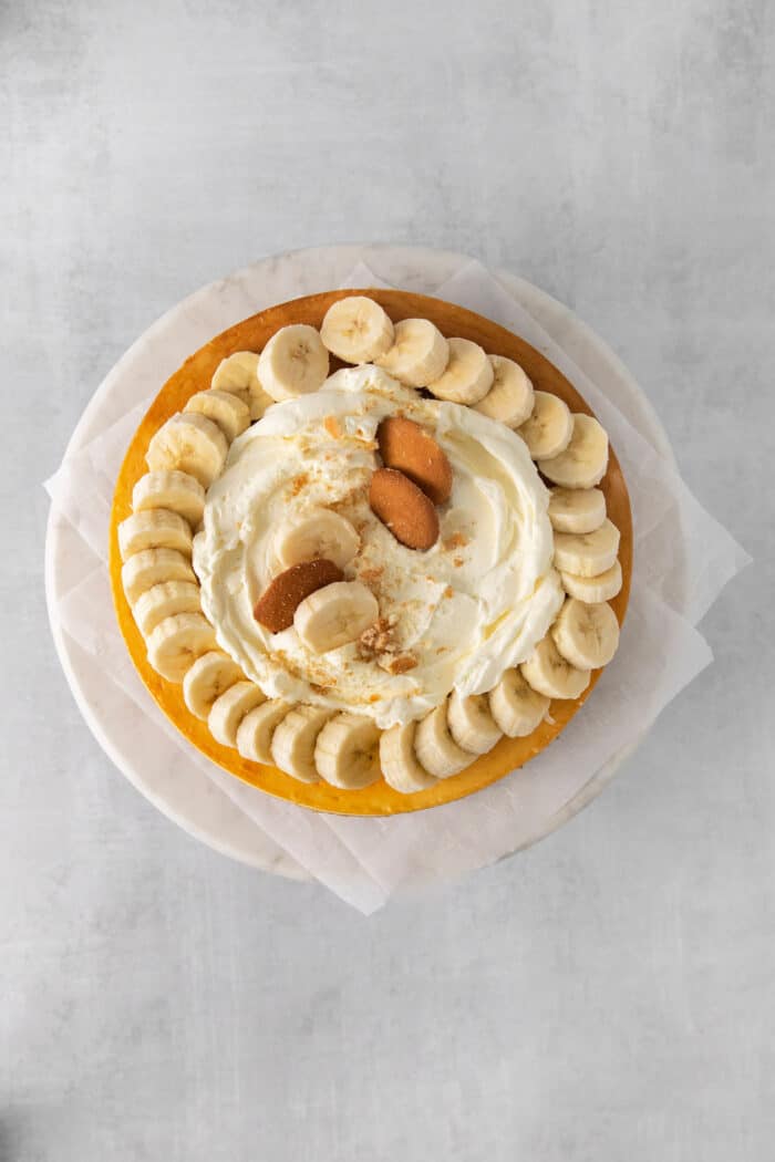 Overhead view of a banana cheesecake topped with whipped cream and bananas
