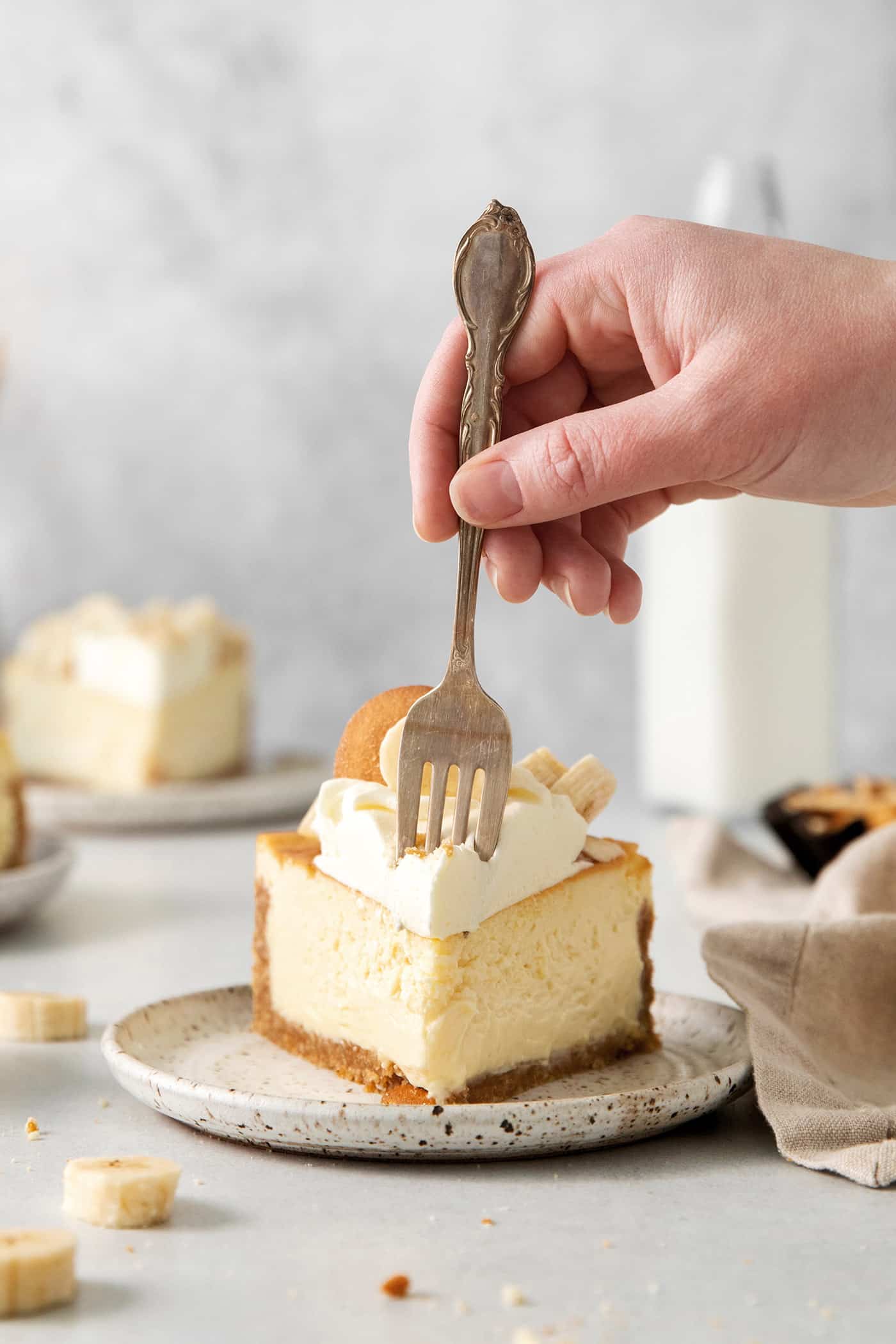 A fork diving into a slice of banana cheesecake