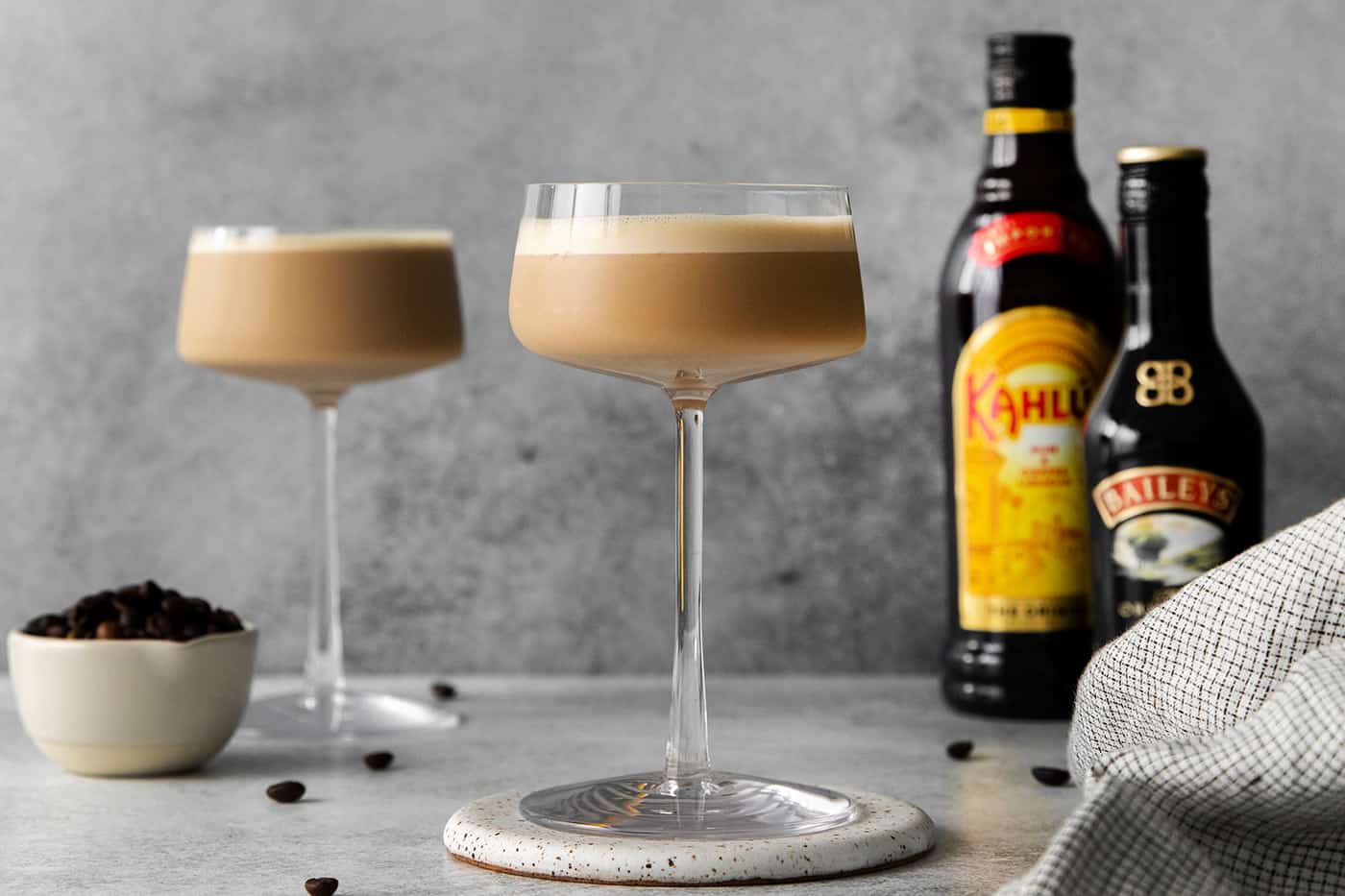 Two espresso martinis next to bottles of Kahlua and Baileys