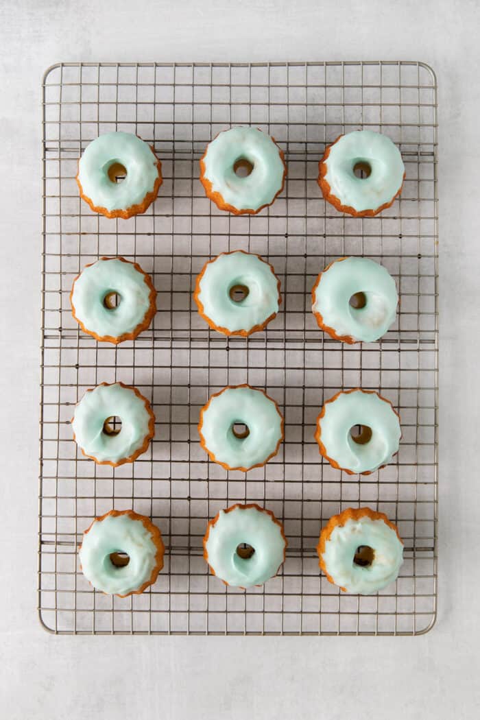 Mini bundt cakes topped with blue icing on a cooling rack