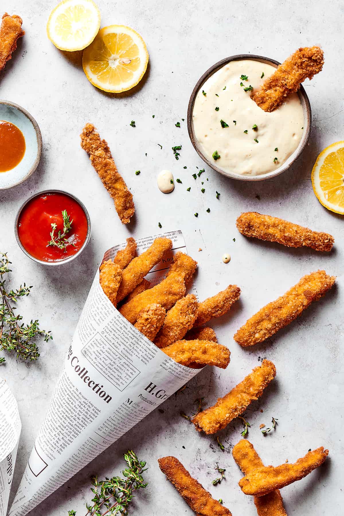 Chicken fries wrapped in a newspaper funnel with various dipping sauces