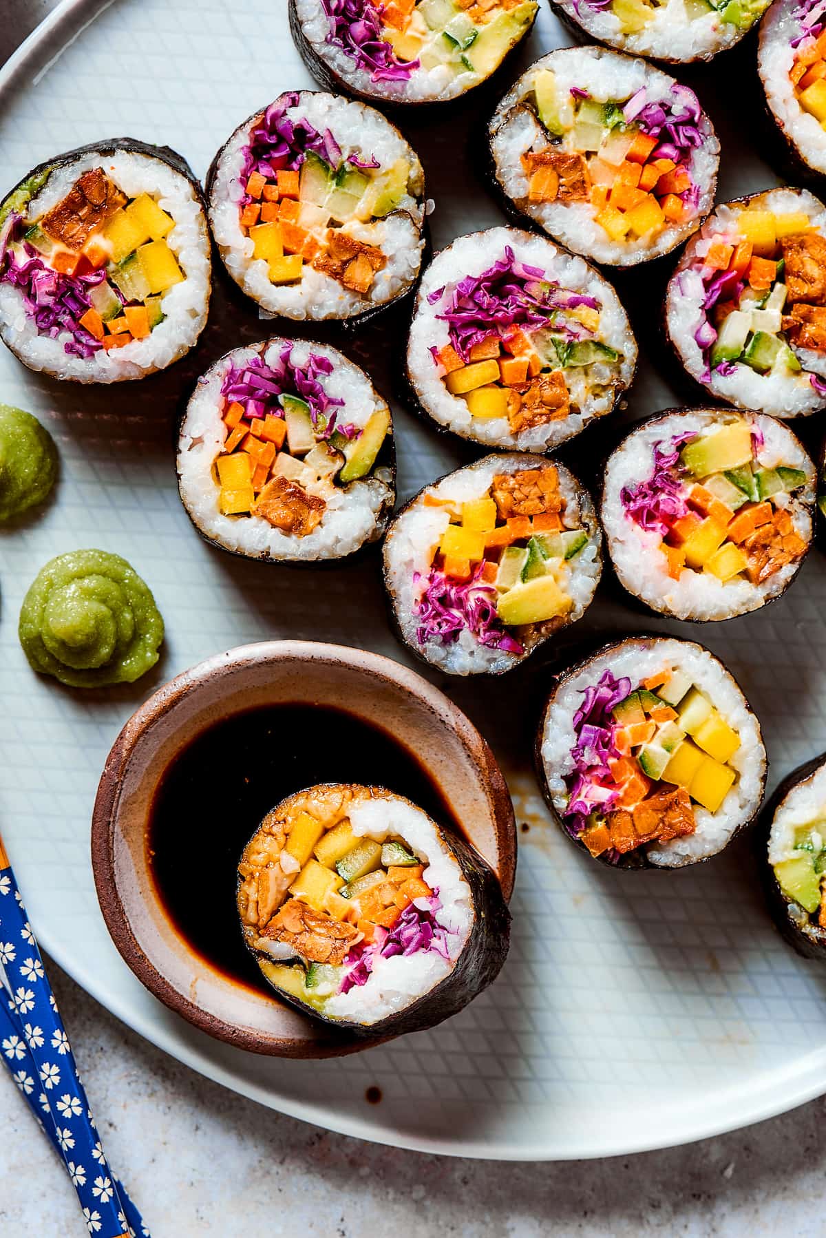 Close up of pieces of vegan sushi with one in soy sauce