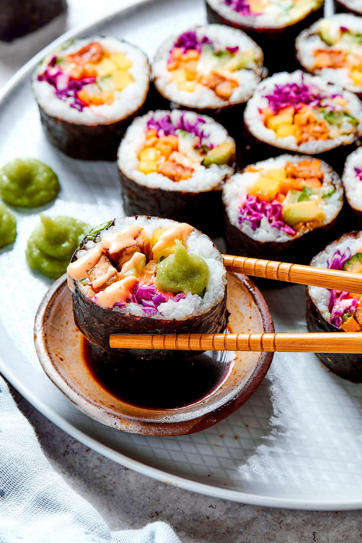 Chopsticks dipping a piece of sushi into soy sauce