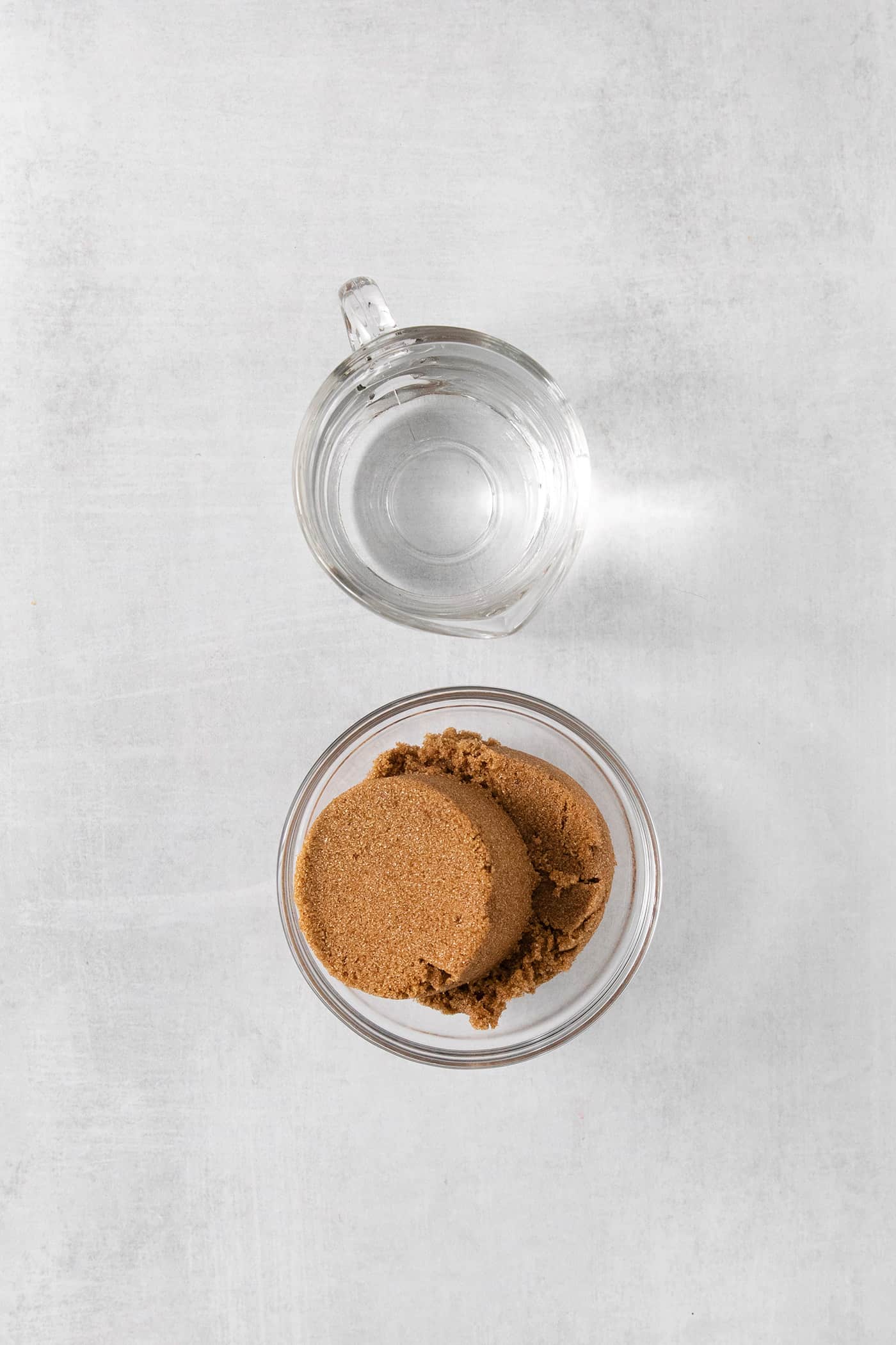 A glass of water and a bowl of brown sugar