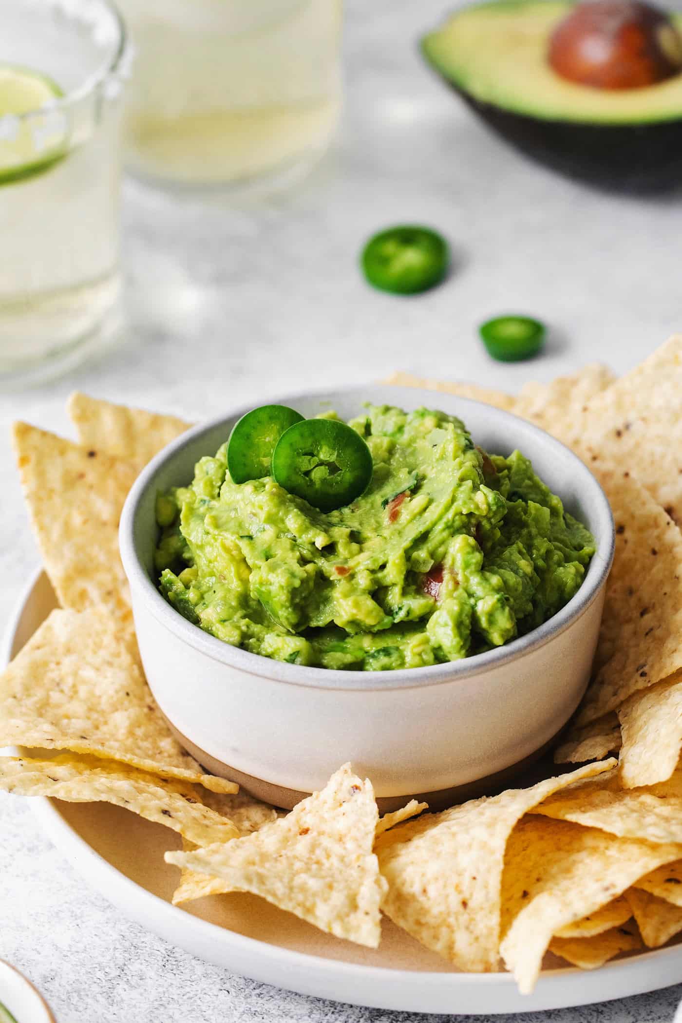 This Classic Homemade Guacamole is fresh and chunky with plenty of lime juice, ripe tomatoes, and crisp cilantro. Homemade guacamole in a bowl surrounded by tortilla chips
