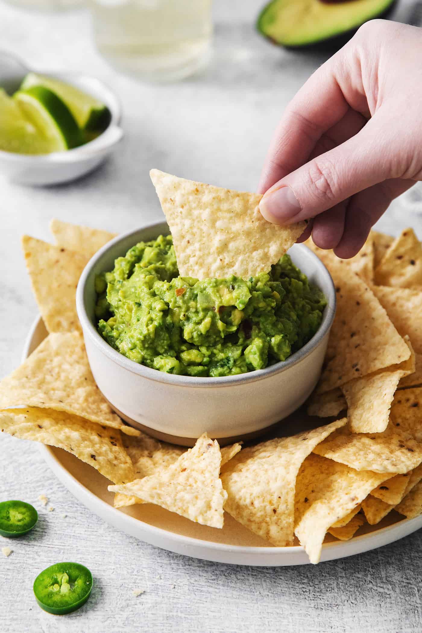 A hand dipping a chip into some fresh guacamole