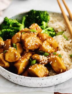 Angled overhead view of a plate of mandarin chicken with rice and broccoli