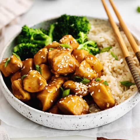 Angled overhead view of a plate of mandarin chicken with rice and broccoli