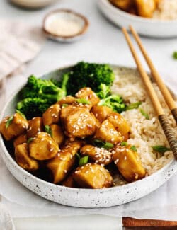 A plate of mandarin chicken with rice and broccoli