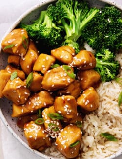 A plate of mandarin orange chicken with rice and broccoli