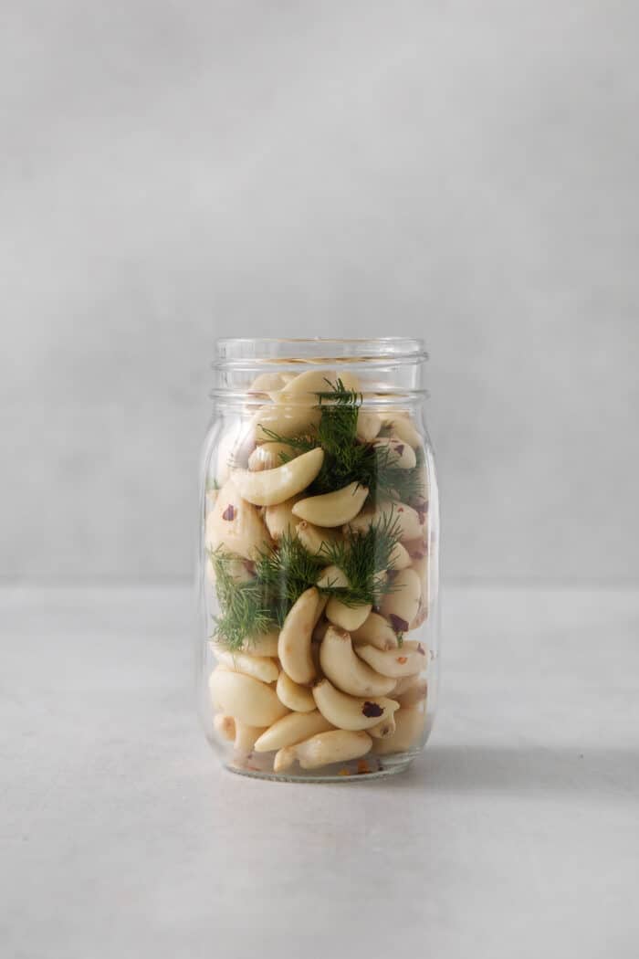A jar of garlic cloves and herbs