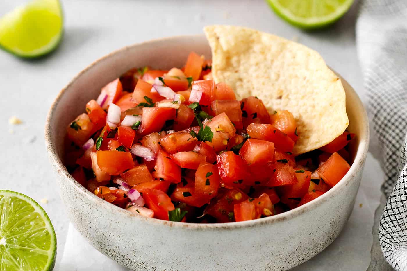 A tortilla chip in a bowl of pico de gallo