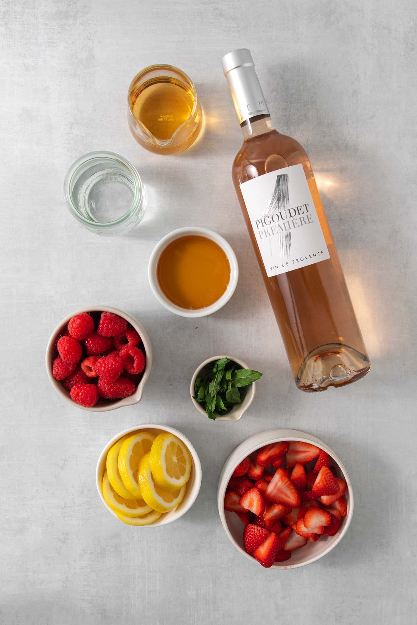 Ingredients for rose sangria are shown, including, wine, fruit, water, and honey.
