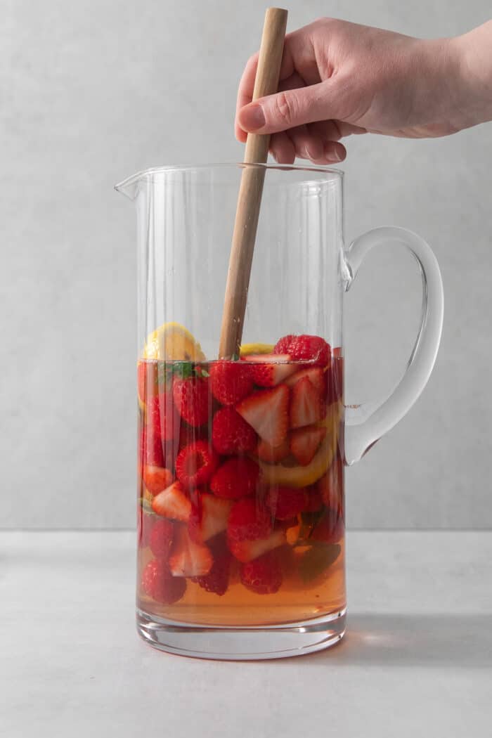 A spoon stirs a pitcher of rose sangria.
