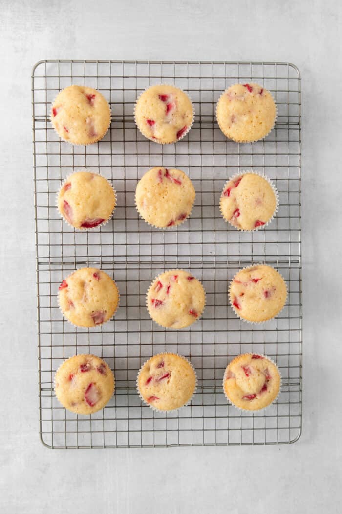 An overhead photo of a dozen unfrosted strawberry cupcakes.