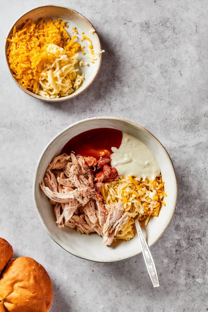 Mixing the ingredients for buffalo chicken sliders in a bowl.