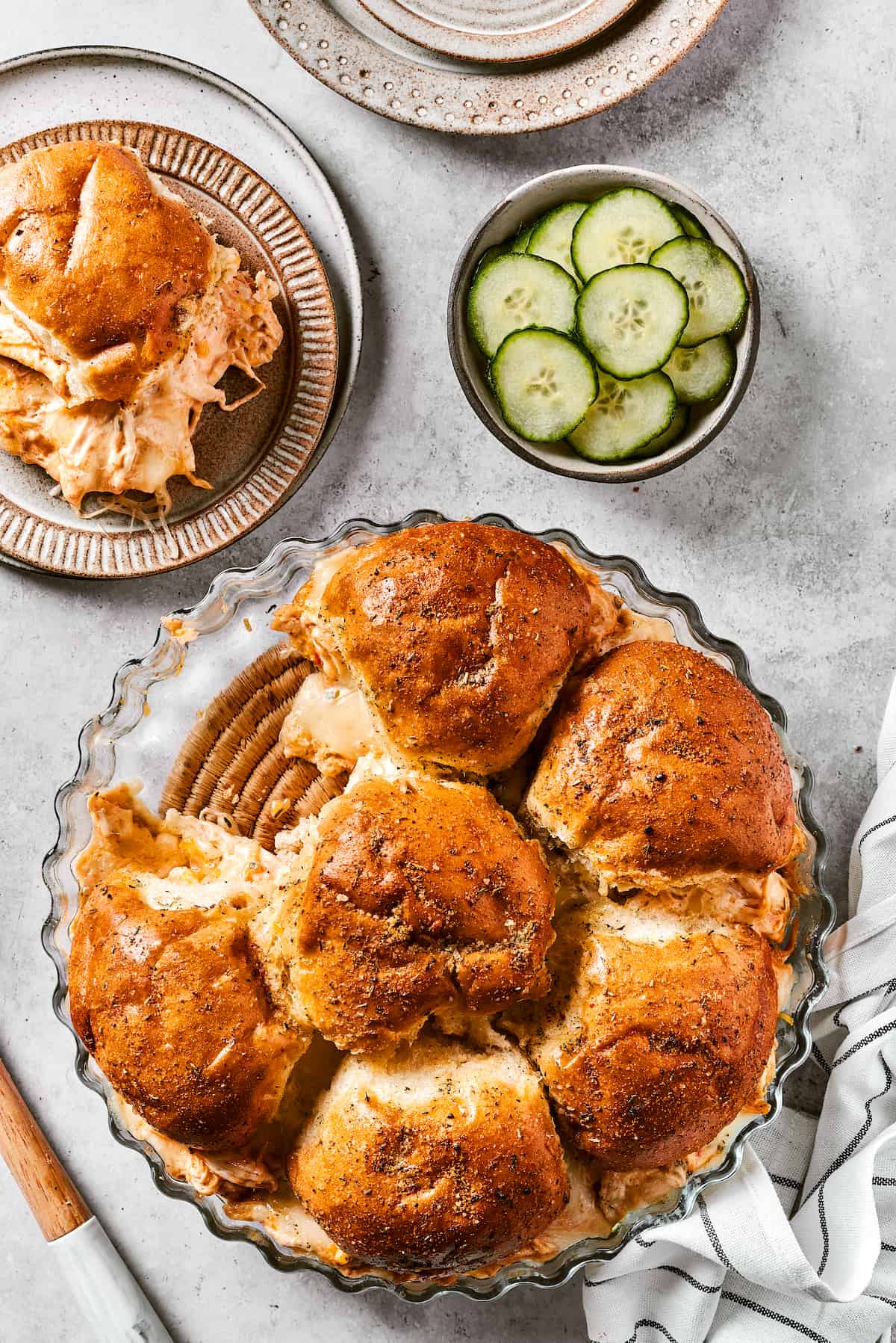 Buffalo chicken sliders are shown on plates with more sliders ready to serve.